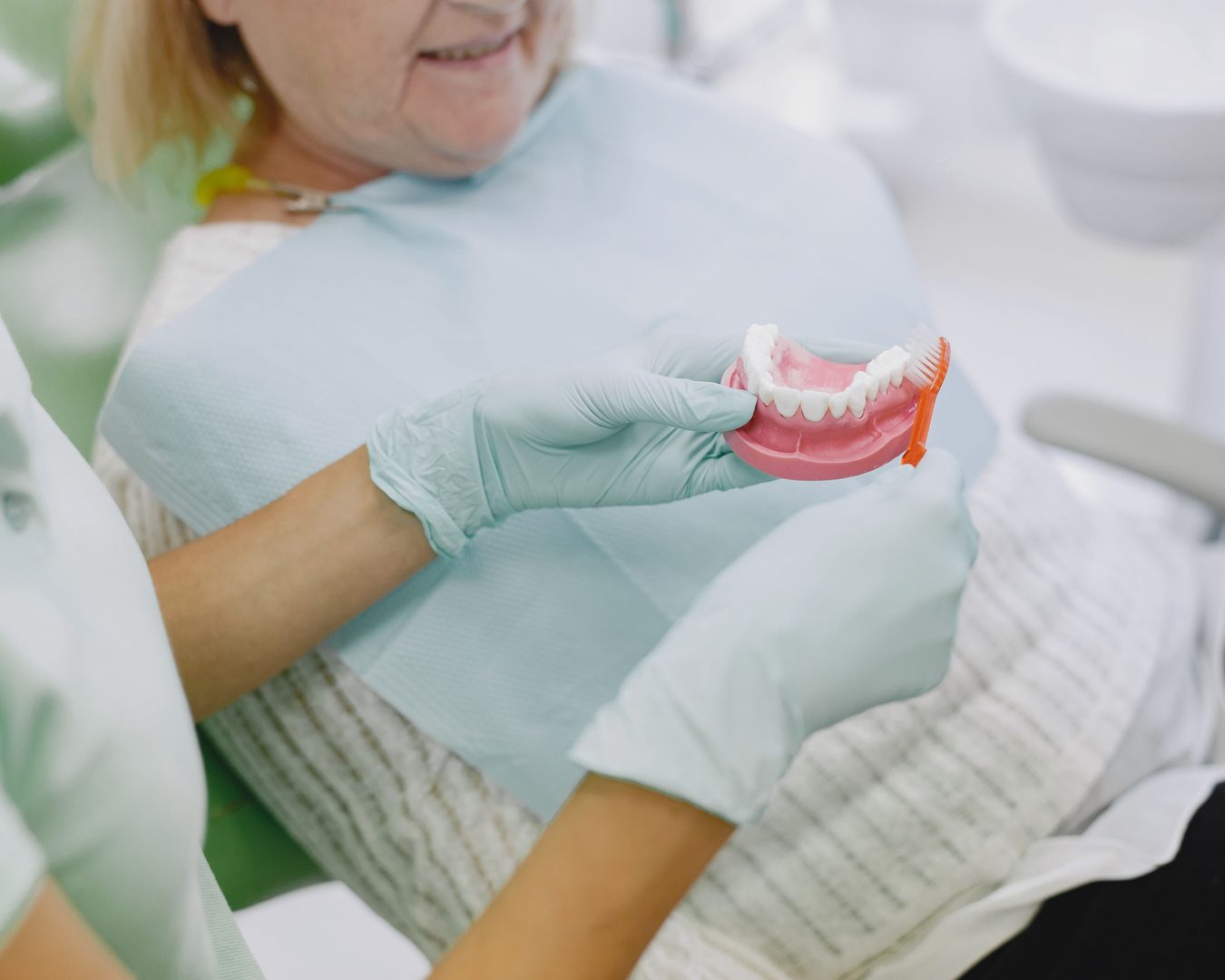 Cuándo se necesita una prótesis dental Dentista muestra una prótesis dental a una paciente sentada en el sillón